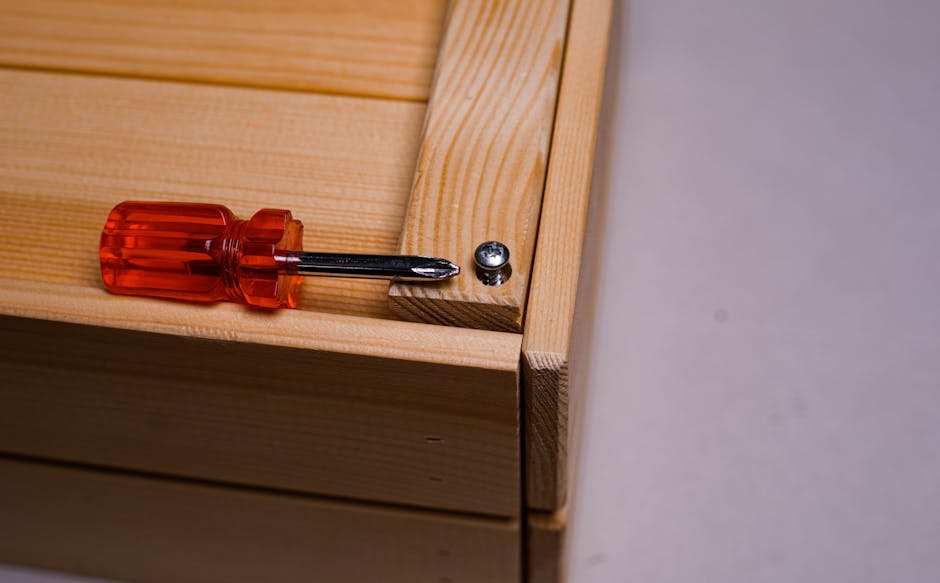 A screwdriver beside a screw on a wooden box, depicting carpentry work.