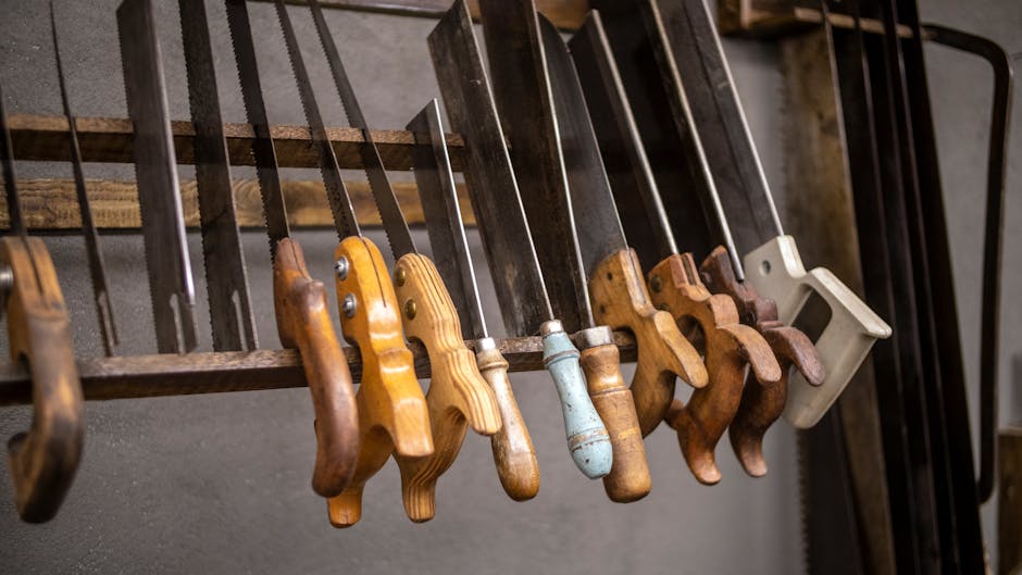 Assorted vintage hand saws with wooden handles neatly displayed in a workshop setting.