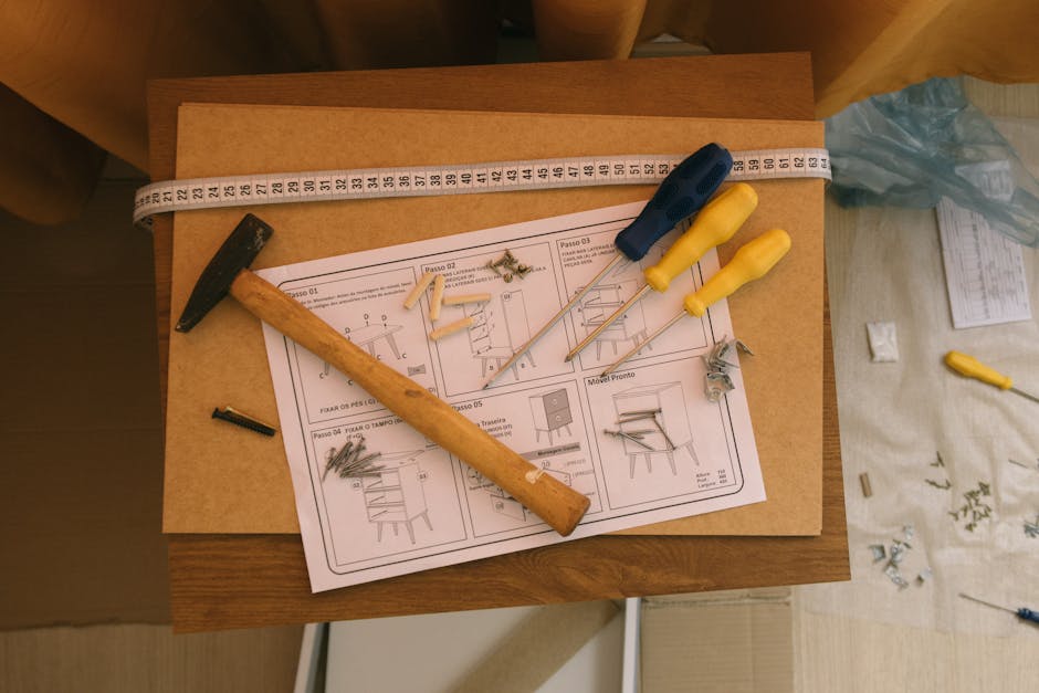 From above of paper instruction helping to assemble furniture with screwdrivers and hammer on top