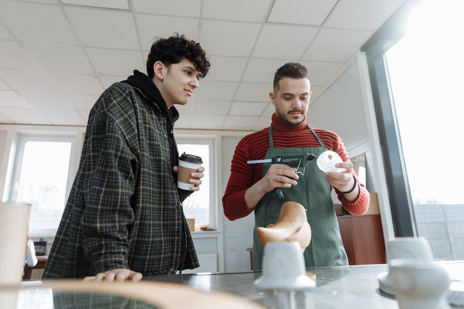 Two young men in a crafting workshop working with a glue gun, focusing on craftsmanship indoors.