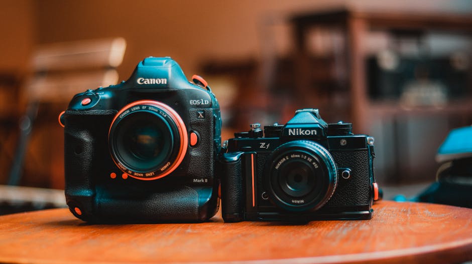 Close-up of Canon and Nikon cameras on a wooden surface indoors.