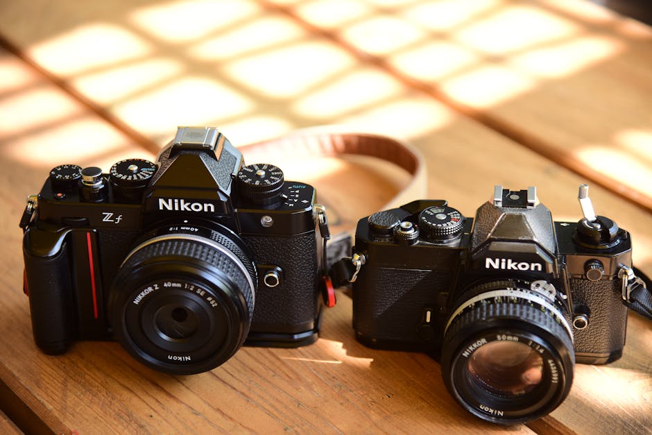 Close-up of vintage and modern Nikon cameras on a wooden table, showcasing design evolution.
