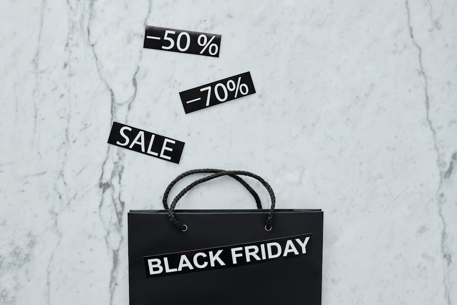 Creative flat lay of Black Friday shopping bag and sale tags on marble surface.