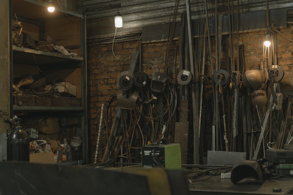 Dimly lit workshop filled with tools, machinery, and metal supplies.