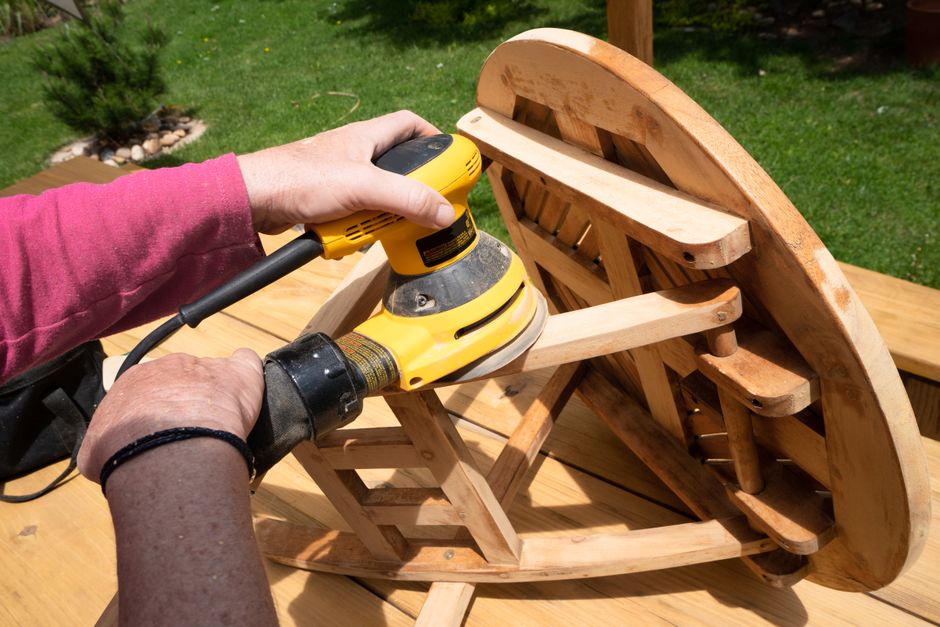 A person using a power sander on a wooden table outside in Boulder, Colorado.
