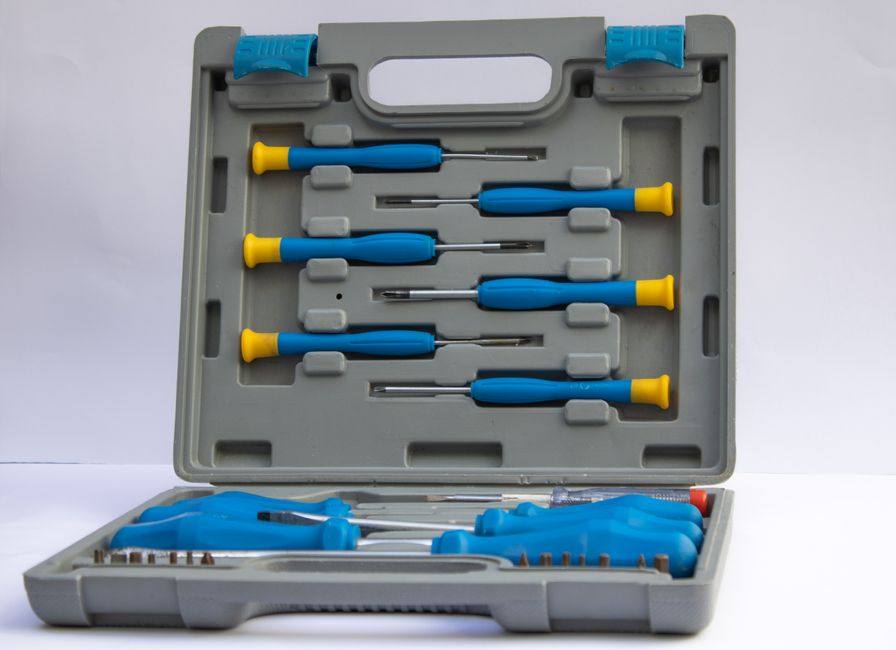 An open gray plastic toolbox displaying an assorted set of screwdrivers with blue handles.
