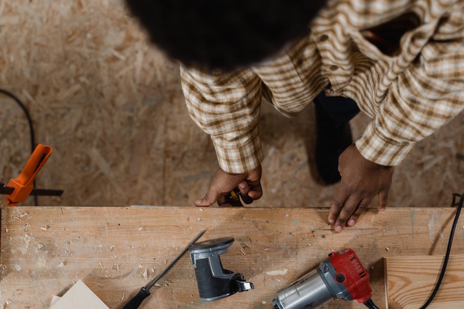 Carpenter working on a wooden project using hand tools and power tools from a high-angle view.