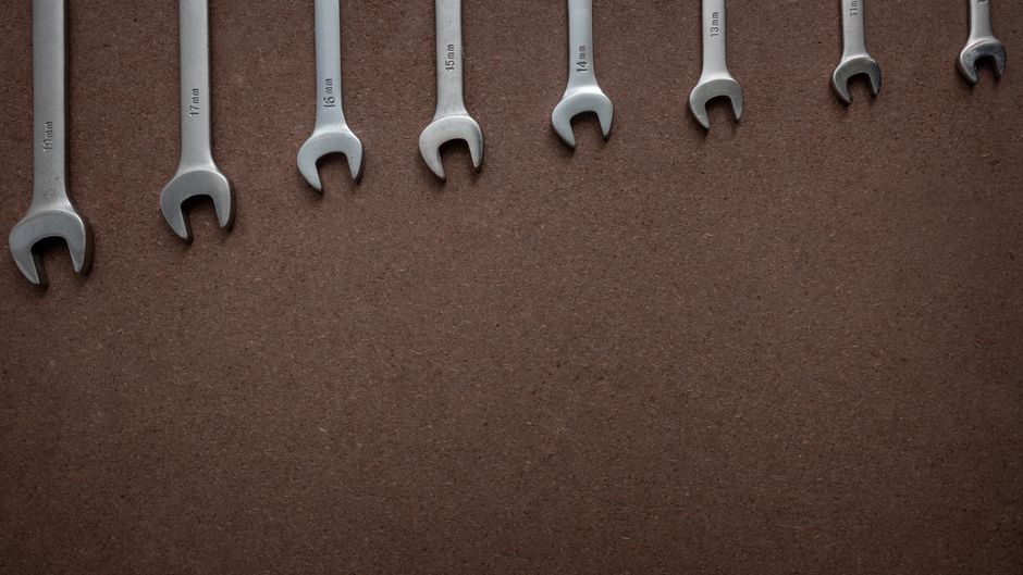Top view of wrenches lined up on a textured brown surface, showcasing sizes.