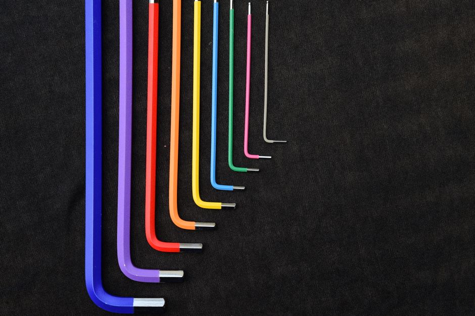 Vibrant array of L-shaped hex keys organized by size on a black surface.