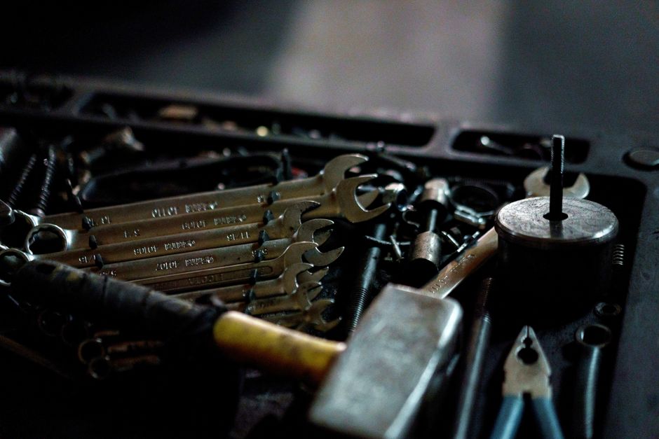 A collection of hand tools including wrenches and a hammer in a toolbox, suitable for repair work.