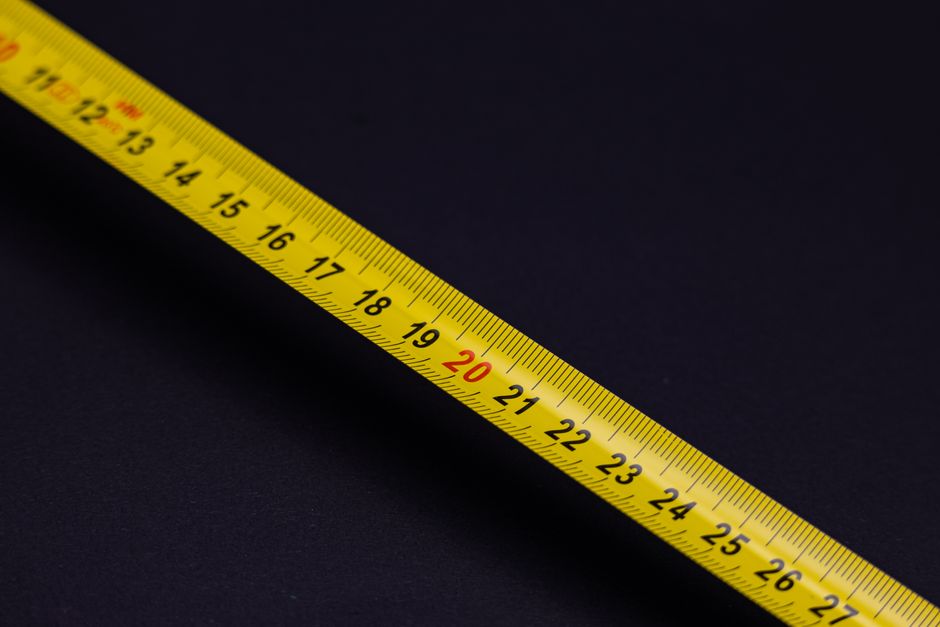 A detailed close-up of a yellow measuring tape against a black background, emphasizing precision and measurement.