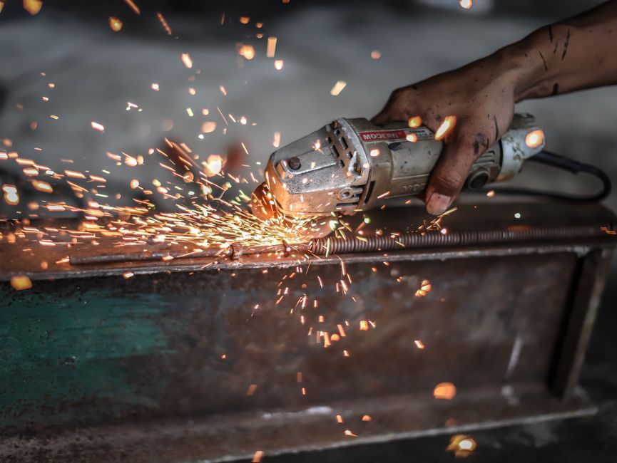 Close-up of a metalworker using a grinder with sparks flying, showcasing precision and skill.
