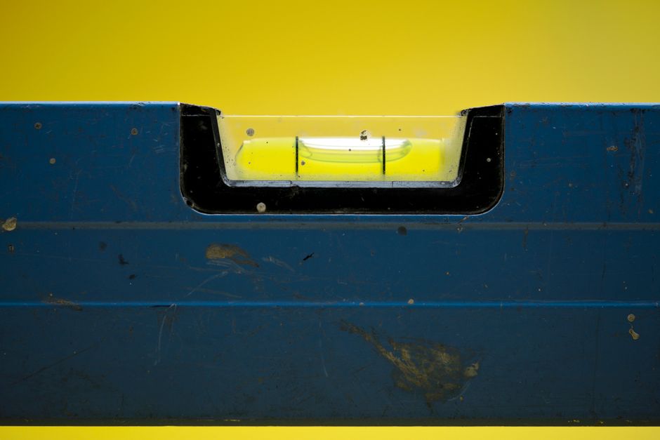 Detailed view of a spirit level with a vibrant yellow backdrop.