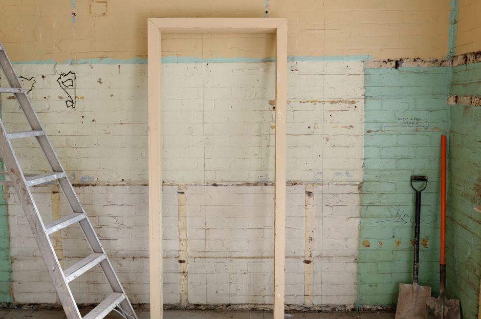 Renovation scene featuring ladder, frame, and tools against partially demolished walls.