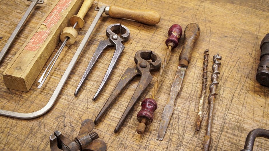 A collection of rusty vintage tools displayed on a wooden workbench, showcasing woodworking history.