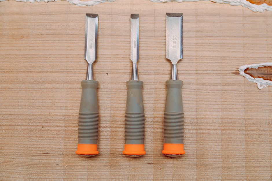 A flat lay of three metal chisels on a wooden surface, perfect for woodworking tools stock image.