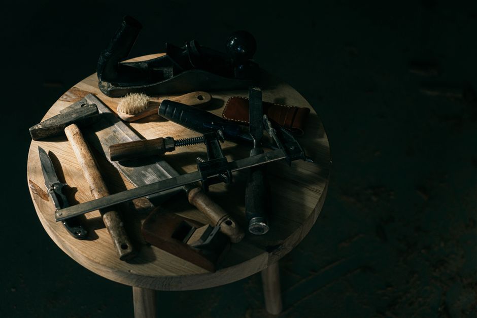 A selection of vintage woodworking tools displayed creatively on a round wooden table.