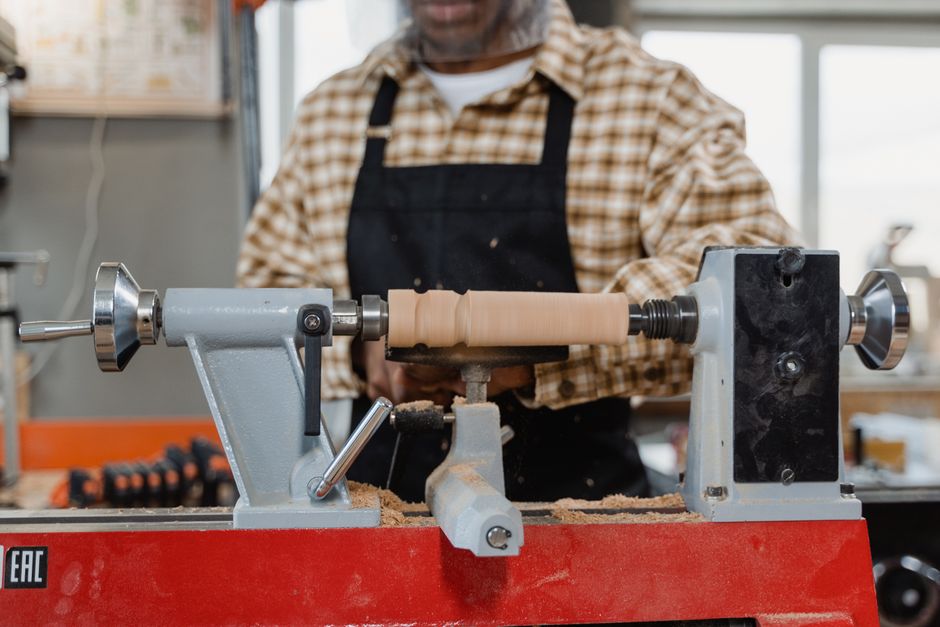 Close-up of a craftsman using a lathe in a workshop, showcasing woodworking skills.