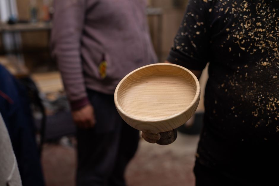 Close-up of a handmade wooden bowl in a craftsman's workshop, highlighting artisanal skill.