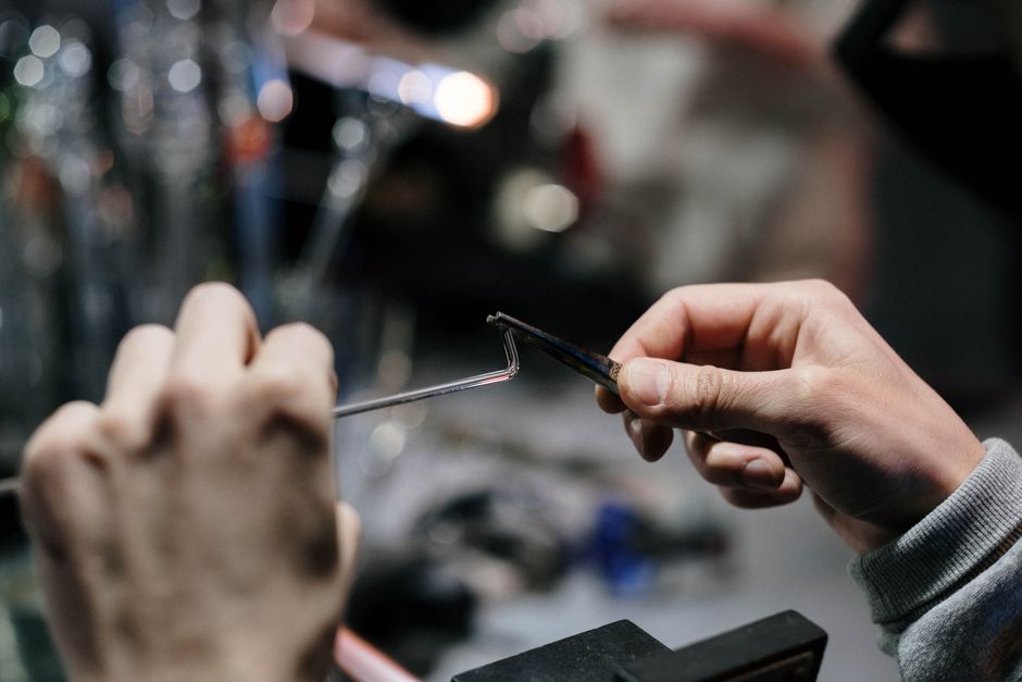 Close-up of an artisan shaping glass with precision tools in a workshop.
