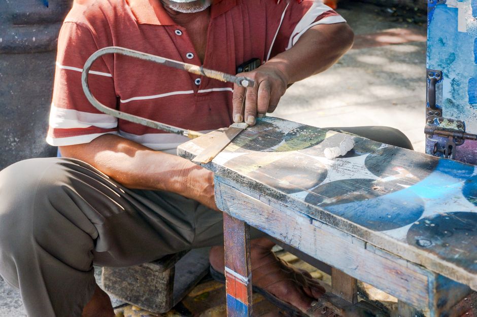 Close-up of an artisan skillfully using a saw outdoors on a sunny day.