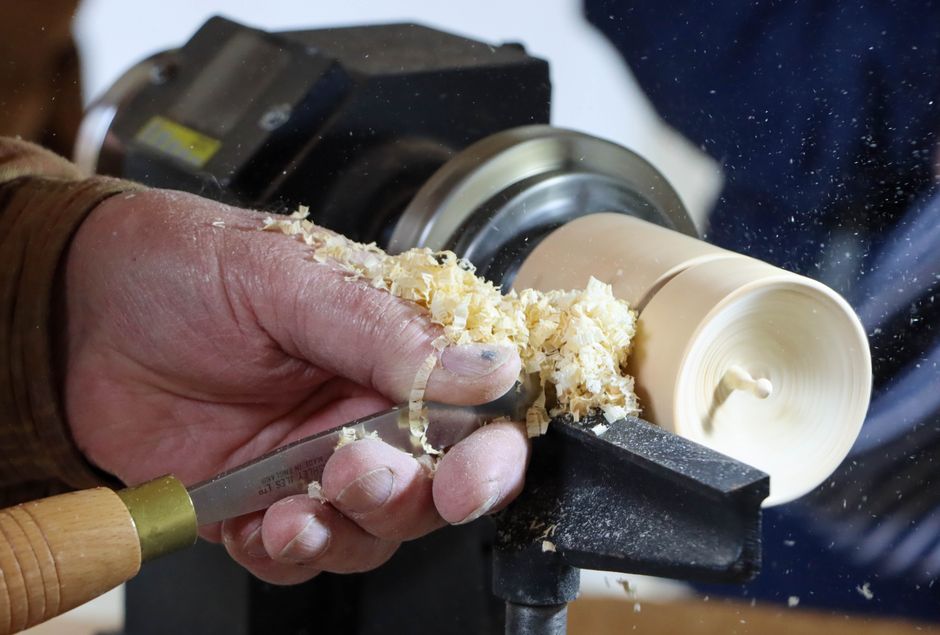 Close-up of woodturner shaping wood on a lathe, showcasing craftsmanship.