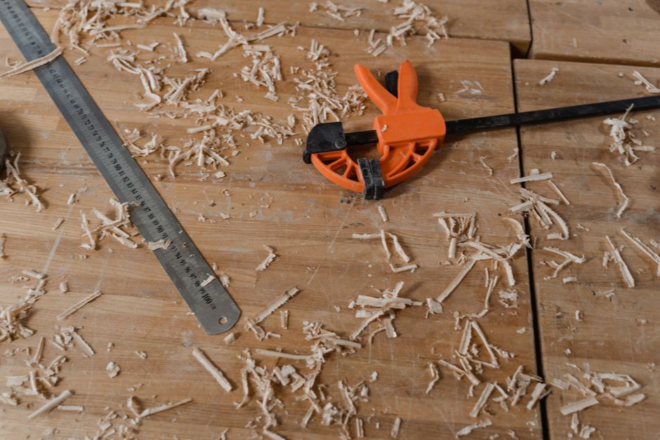 Close-up of woodworking tools on a wooden workbench with scattered sawdust.