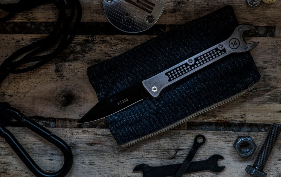 Detailed arrangement of metal tools and accessories on a wooden table, featuring a pocket knife.