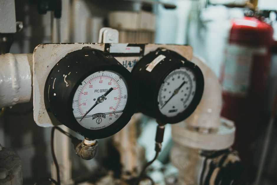 Detailed close-up of industrial pressure gauges set against a blurred machine background.