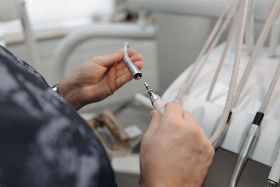 Detailed view of a dentist's hands preparing dental tools in a modern clinic setting.