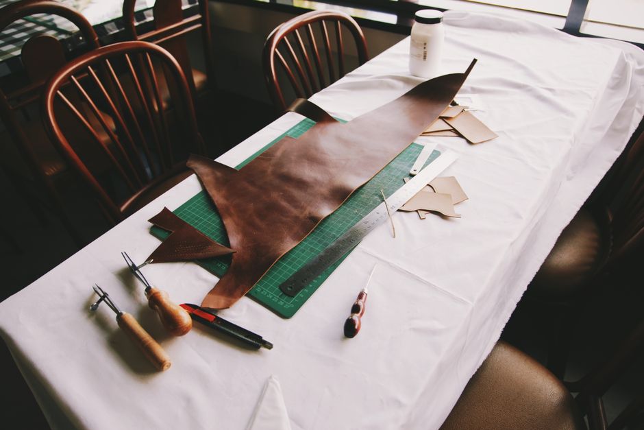 Intricate leather crafting setup with tools on a workshop table in Jakarta.