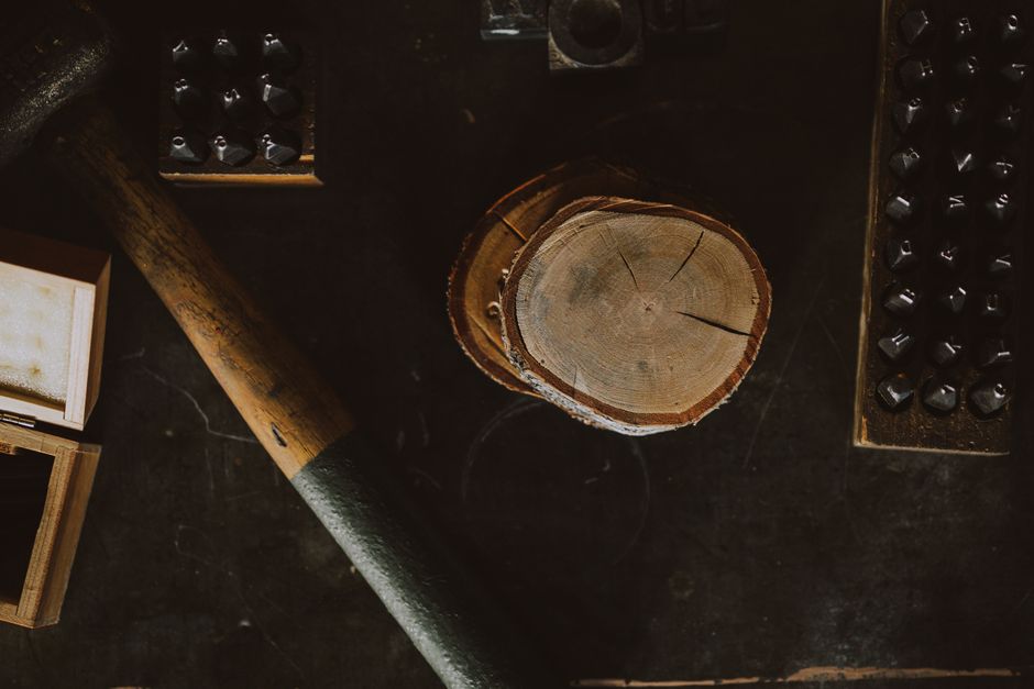 Top view of a wood log and tools on a workbench, capturing a rustic workshop setting.