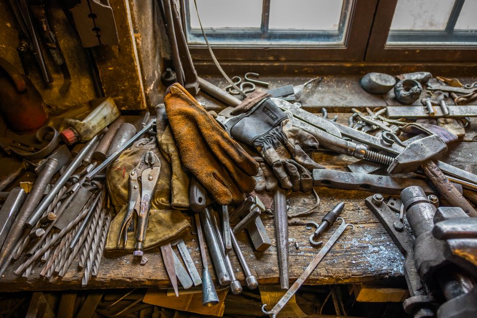 A cluttered workbench filled with various vintage tools in a rustic workshop setting.