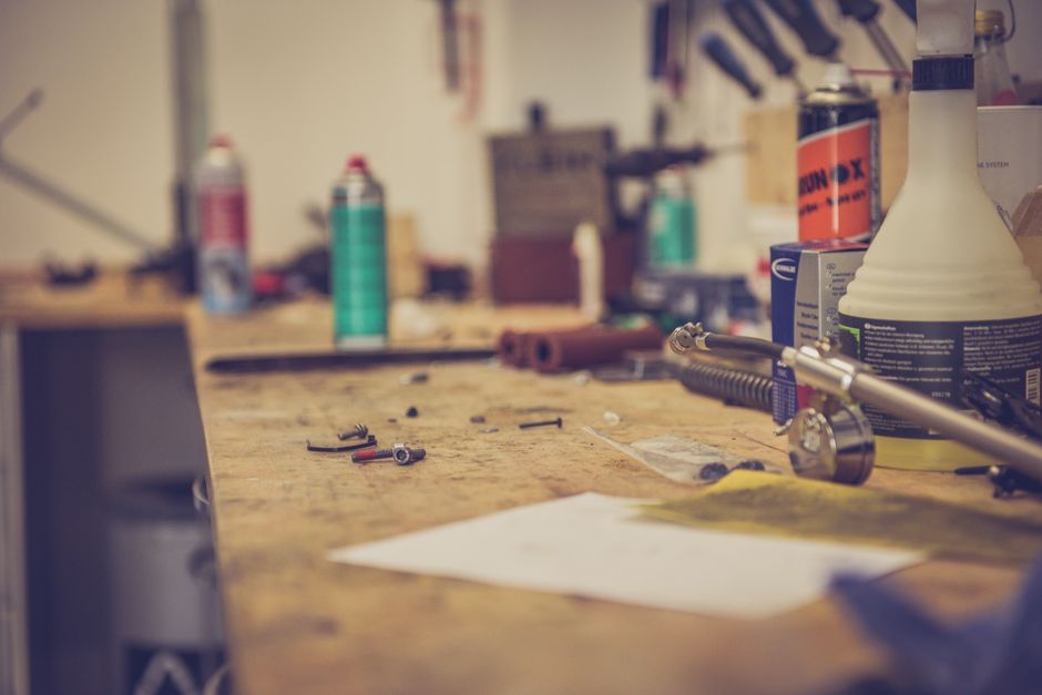 A cluttered workbench in a workshop with various tools and materials for maintenance.