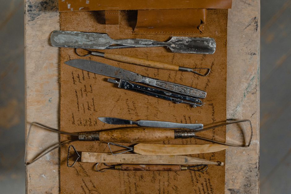 A selection of vintage artisan tools laid out on a rustic wooden table, showcasing craftsmanship history.