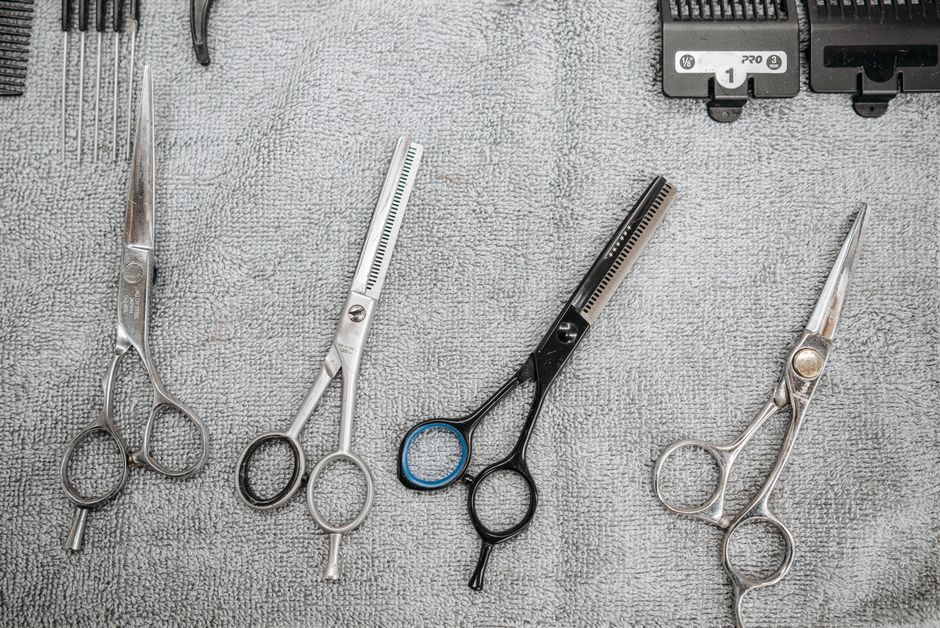 A set of professional haircutting scissors and tools neatly arranged on a grey towel.