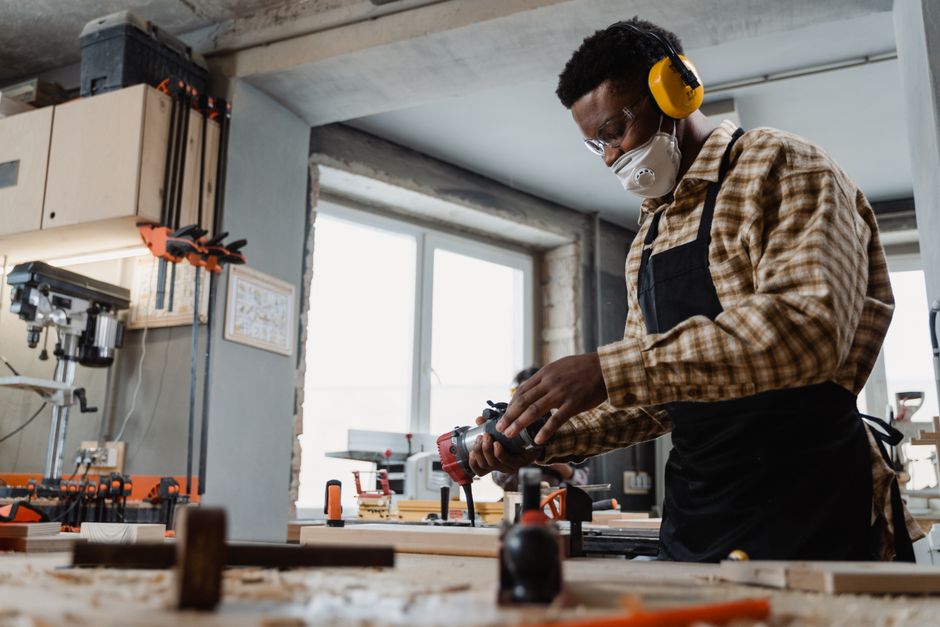 Focused craftsman using power tools in a modern woodworking workshop.