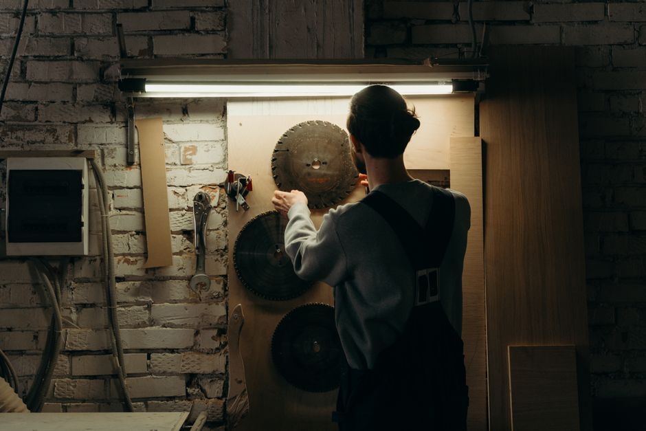 Man arranging tools in a workshop with circular saw blades on display.