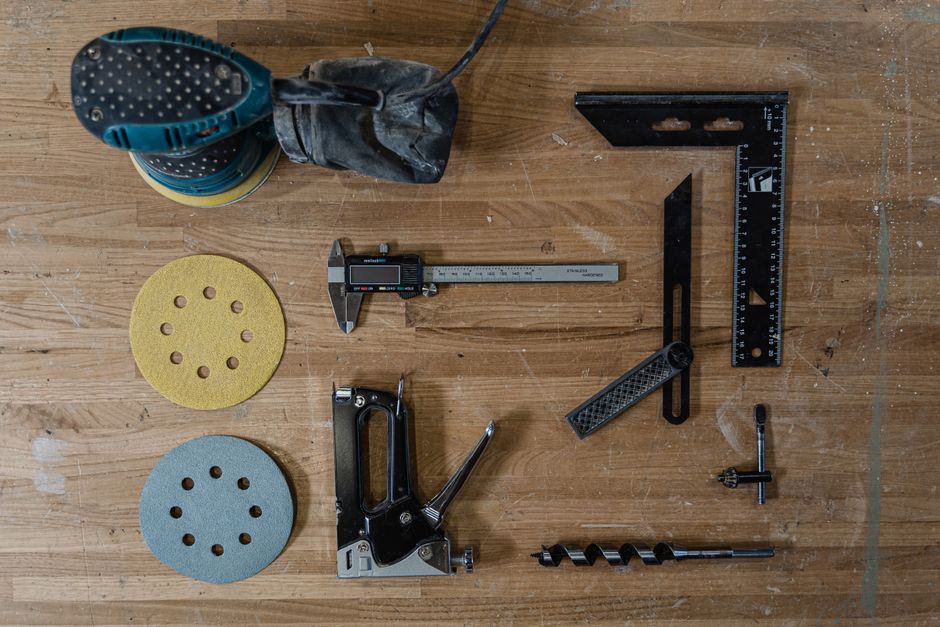 Wide assortment of woodworking tools neatly arranged on a wooden workbench top.