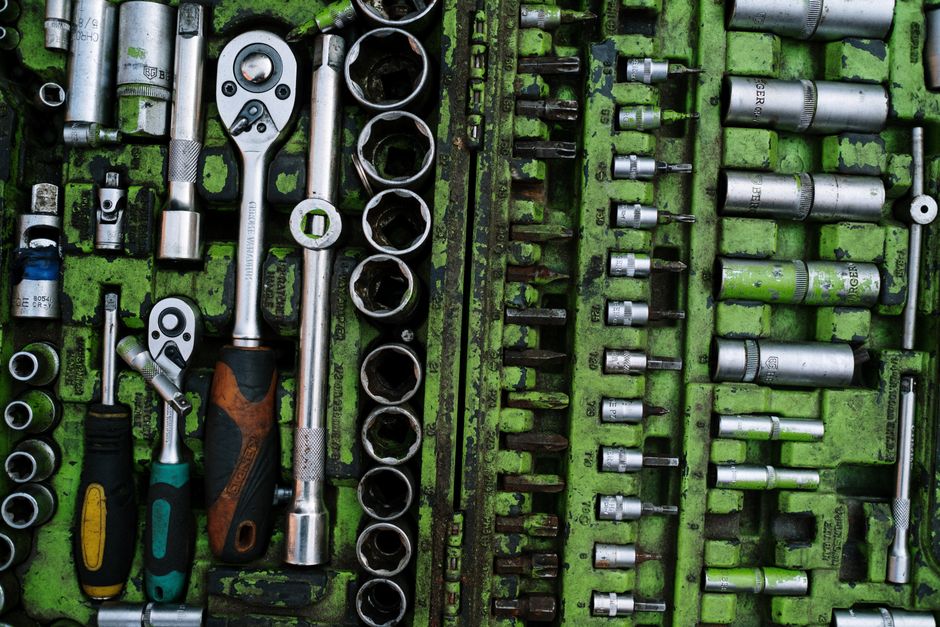 A well-organized set of metal tools in a green toolbox with ratchets and screwdrivers.